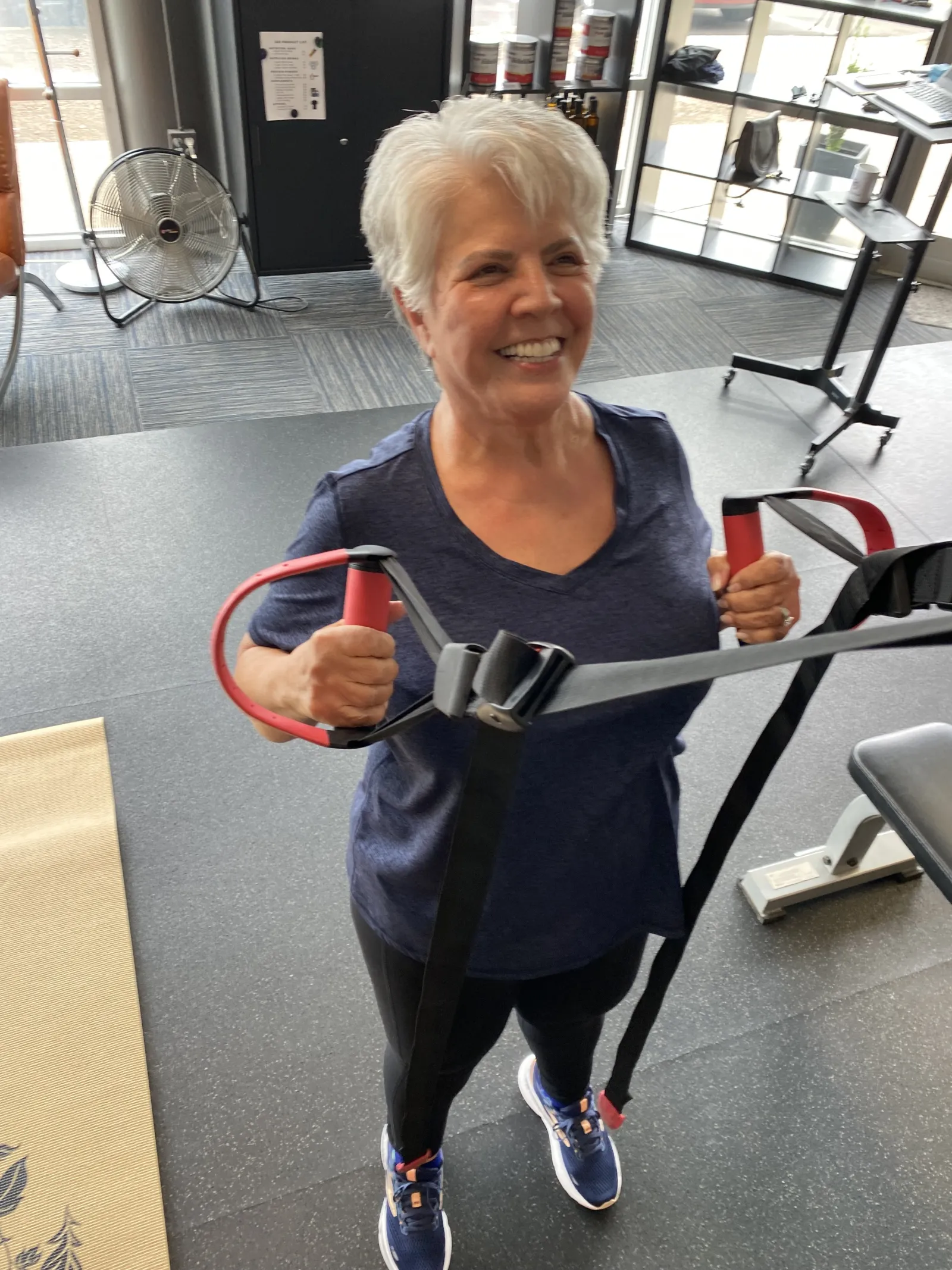 A smiling member training with suspension handles