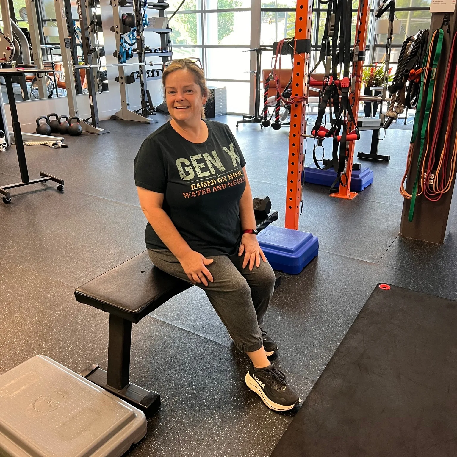 A smiling member resting on a bench between sets