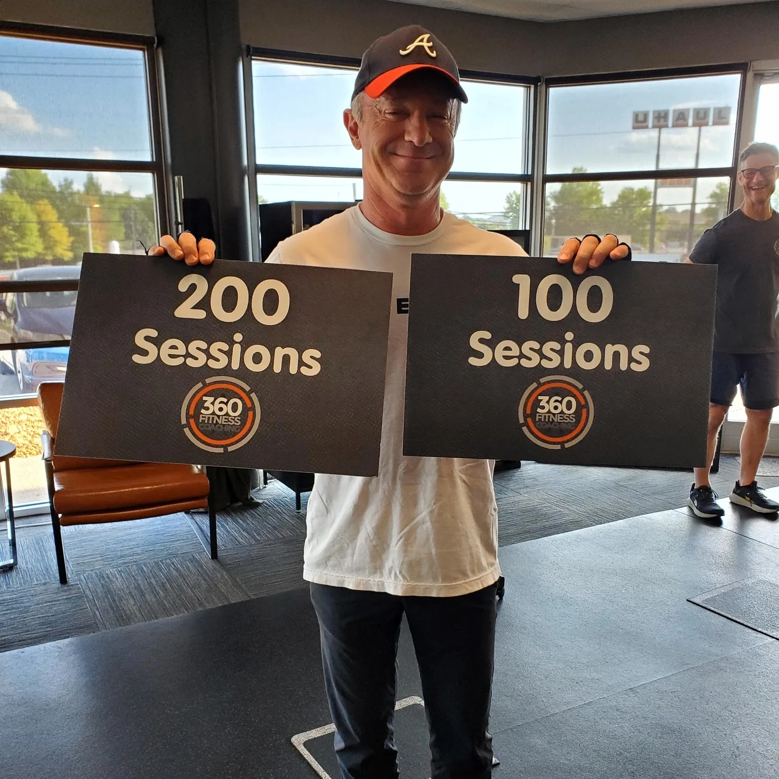 A member holding 200 Sessions and 100 Sessions milestone signs